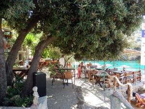 un groupe de tables et de chaises sous un arbre à côté d'une piscine dans l'établissement Apartments Vladilena, à Utjeha-Bušat