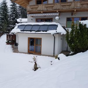 uma casa com neve no chão em frente dela em Ferienwohnung Prama em Going