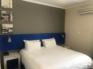 a bedroom with a large white bed with a blue headboard at Premier Splendid Inn Bayshore in Richards Bay