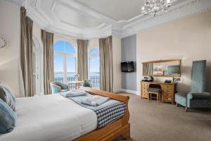 1 dormitorio con cama, escritorio y espejo en Giltar Hotel, en Tenby