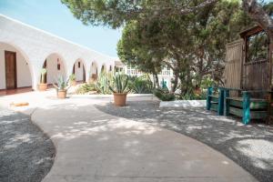 a walkway with a green bench and some trees at Hostal La Torre Ibiza Cap Negret in San Antonio