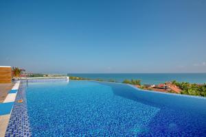 a large swimming pool with the ocean in the background at Fivitel Hoi An Hotel in Hoi An