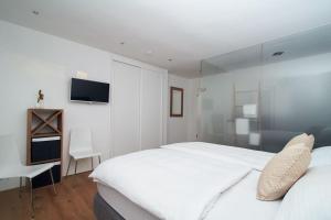 a white bedroom with a large bed and a desk at Loft Rebhalde in Nonnenhorn