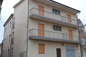 a white building with orange doors and balconies on it at White beach Le Castella in Le Castella