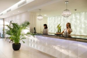 two women standing at a counter in a lobby at Tomir Portals Suites - Adults Only in Portals Nous