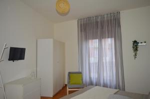 a bedroom with a bed and a chair and a window at White beach Le Castella in Le Castella