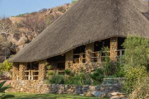 a stone building with a grass roof at Ondundu Lodge in Kamanjab
