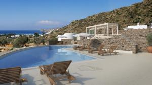 a swimming pool with a bunch of chairs around it at Ostria Village in Mylopotas