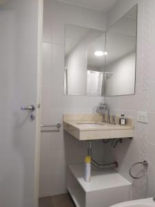 a white bathroom with a sink and a mirror at Departamento Parque Alem in Rosario