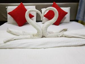 Dois cisnes de toalhas numa cama com almofadas vermelhas em Hotel Mrk em Varanasi