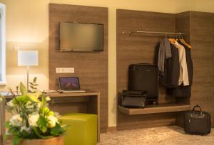 a room with a wall with a television and a desk at Hotel Jakob Regensburg in Regensburg