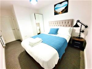 a bedroom with a large bed with a blue blanket at Manchester Holiday Apartment in Manchester
