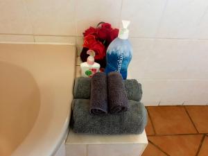a bathroom with a toilet and a bottle and towels at SnL 38 Hoep Hoep in Malelane +1 photo