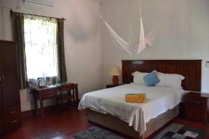 Schlafzimmer mit einem Bett, einem Tisch und einem Fenster in der Unterkunft Tabonina Bis in Livingstone