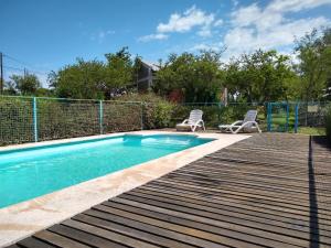 una piscina con 2 sillas en una terraza de madera en Cabañas Rayuela y otros cuentos en Santa Rosa de Calamuchita