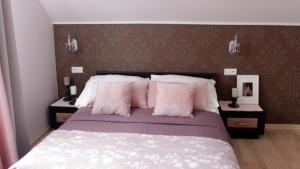 sypialnia z dużym łóżkiem z różowymi poduszkami w obiekcie Koralia Domki i Apartamenty w Sarbinowie