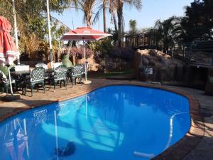 uma piscina com uma mesa e um guarda-sol em Ambassador Lodge Kimberly em Kimberley