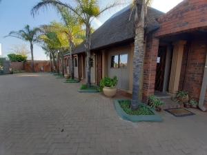 um edifício de tijolos com palmeiras ao lado de uma entrada em Ambassador Lodge Kimberly em Kimberley