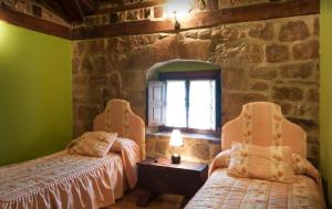 a bedroom with two beds and a stone wall at Casa Rural La Panera in Cillamayor