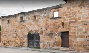 una vieja pared de ladrillo con una puerta y una puerta en Casa Rural La Panera en Cillamayor