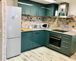 a kitchen with green cabinets and a white refrigerator at Con Piscina Confort Nordico Aranjuez garaje in Aranjuez