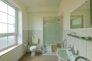 ein weißes Bad mit einem WC und einem Waschbecken in der Unterkunft Hotel intakt in Bedburg