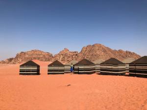 een persoon die voor een rij hutten in de woestijn staat bij Wadi rum desert breath in Wadi Rum