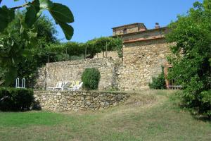 a stone wall with two chairs and a building at CASA ROSSA in Capolona
