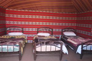 a room with three beds in a red wall at Wadi rum desert breath in Wadi Rum