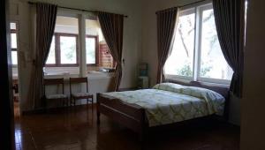 ein Schlafzimmer mit einem Bett in einem Zimmer mit Fenstern in der Unterkunft Bunga Ayu Seaside Resort in Pelabuhan Ratu