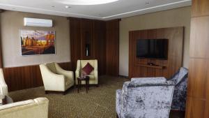 Camera con 2 sedie e TV a schermo piatto di Taleen AlMasif hotel apartments a Riyad