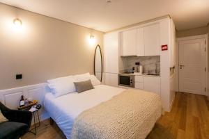 a bedroom with a white bed and a kitchen at Charming Studio in Historic Downtown in Porto