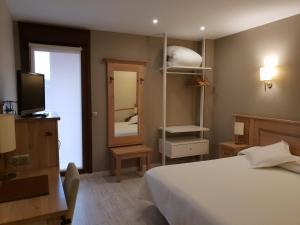 a bedroom with a bed and a tv and a mirror at Hotel A Boira in Jaca