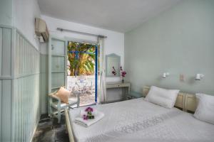 a bedroom with a bed with a table and a window at Aegean Village in Parikia