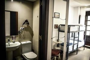 
a bathroom with a toilet, sink and mirror at The Lights Hostel in Málaga
