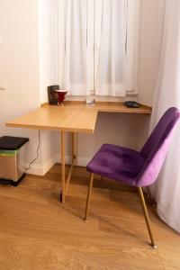 una scrivania in legno con sedia viola accanto a una finestra di Design Studio Flat with Terrace Next Toledo Metro Stop a Napoli