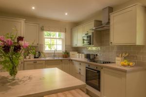 a kitchen with white cabinets and a vase of flowers at Quarry Gardens Lodge in Fochabers