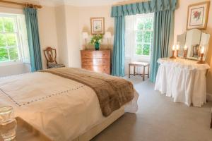 a bedroom with a bed and a table and windows at Quarry Gardens Lodge in Fochabers