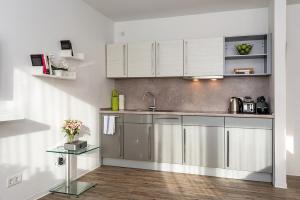 una cucina con elettrodomestici in acciaio inossidabile e armadietti bianchi di Apartments Rosenthal Residence a Berlino