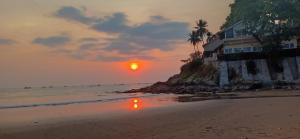 Bunga Ayu Seaside Resort في بلابون راتو: منزل على الشاطئ مع غروب الشمس