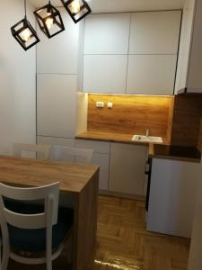 eine Küche mit einem Holztisch und weißen Schränken in der Unterkunft Dunja in Valjevo