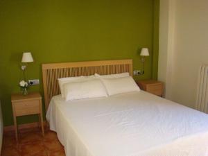 1 dormitorio con 1 cama blanca y paredes verdes en Can Vilafort, en Collsuspina