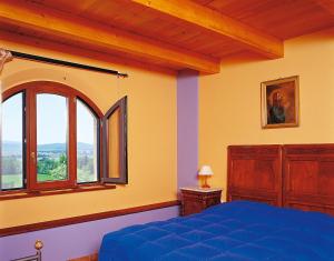 sypialnia z niebieskim łóżkiem i oknem w obiekcie Casavacanze Casalta w mieście Sovicille