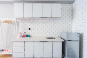 a kitchen with white cabinets and a refrigerator at Quzhu Apartment Hotel (Wuhan Hankou Railway Station) in Wuhan +62 photos