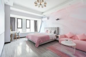 a bedroom with a pink bed and a pink couch at Quzhu Apartment Hotel (Wuhan Hankou Railway Station) in Wuhan