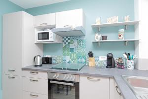 a kitchen with white cabinets and blue walls at Le Petit Clément - F2- 39m2 - Metz - Proche Gare et Centre Pompidou avec Parking Public in Metz