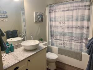 a bathroom with a sink and a toilet and a shower curtain at Sandy Feet Retreat Port Renfrew- Oceanfront 2BR modern cottage in Port Renfrew +14 photos