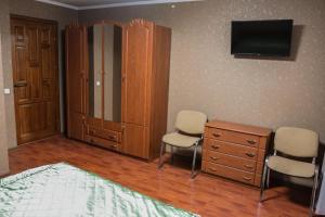 a room with a bed, chair and a tv at Gostynniy Dvir Hostel in Ternopil