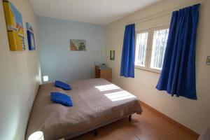 a bedroom with a bed with blue curtains and a window at Windsock Apartment Caribbean Dream in Kralendijk