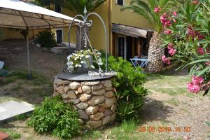 a stone fountain in front of a house with flowers at Appartamenti al mare in SantʼAntìoco